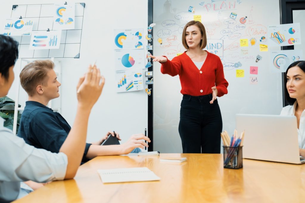 gros plan du chef de projet masculin lève la main pour poser des questions tandis que la jeune chef présente le projet d'entreprise avec confiance en utilisant la carte mentale et les post-it colorés